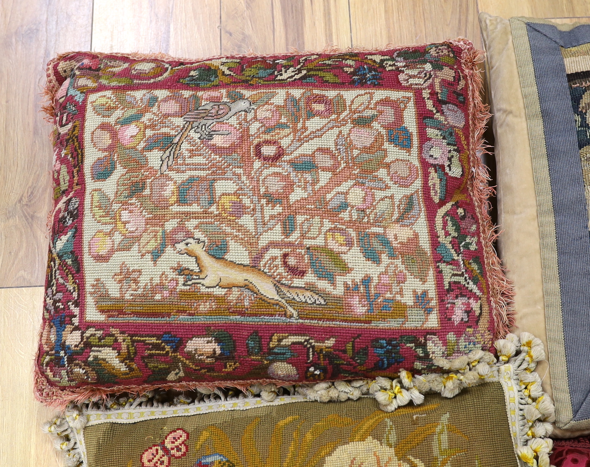 A late 18th century Flemish verdure tapestry fragment made into a cushion, a similar burgundy silk velvet damask cushion and two 19th early 20th century wool worked cushions (4)